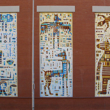 A photo of a three murals side by side on a builinding of abstracted people and animals made up of tiny boxes and stuff.